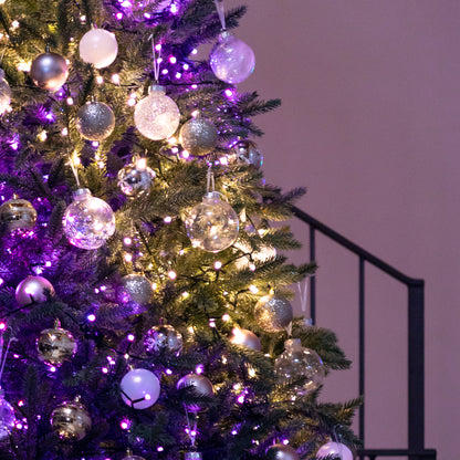 Decorated Christmas tree with purple and silver ornaments against a neutral background